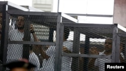 FILE - Mohamed Fahmy (R) and other defendants react at a court proceeding in Cairo, June 23, 2014.