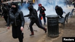 Activistas anti-Trump corren luego que la policía les lanzó granadas de aturdimiento para combatir los destrozos que estaban perpetrando en el centro de Washington antes de la toma de posesión de Donald Trump.