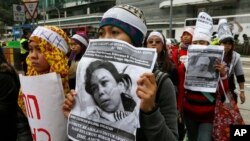 Para pembantu rumah tangga dan pendukung mereka memegang gambar TKI Erwiana Sulistyaningsih, 23, yang diduga disiksa majikannya di Hong Kong, Maret 2014. (AP/Vincent Yu)