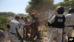 Un joven migrante centroamericano es retenido por sus compañeros, ya que son bloqueados por la Guardia Nacional Mexicana después de cruzar el río Suchiate con un grupo de migrantes de Guatemala a México, en la orilla del río cerca de Ciudad Hidalgo.