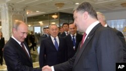 Presiden Rusia Vladimir Putin bersalaman dengan Presiden Ukraina Petro Poroshenko dalam sebuah pertemuan di Minsk, Belarus, Agustus 2014.