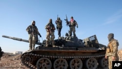Бійці сирійської опозиції стоять на захопленій військовій бронетехніці на околиці Хами, Сирія, у вівторок, 3 грудня 2024 року.