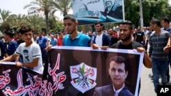 FILE - Hundreds of supporters of exiled former Gaza strongman Mohammed Dahlan carry a banner with his picture during a protest against metal detectors Israel erected at the Al-Aqsa Mosque compound in Jerusalem, in Gaza City, July 20, 2017.