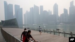 A worker wears a mask as he helps another push equipment during a hazy day in Singapore, Thursday, Sept. 10, 2015. 