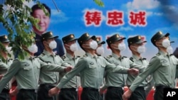 资料照：守卫北京天安门的中国军队士兵走过宣传习近平领导的宣传画。（2020年5月25日）