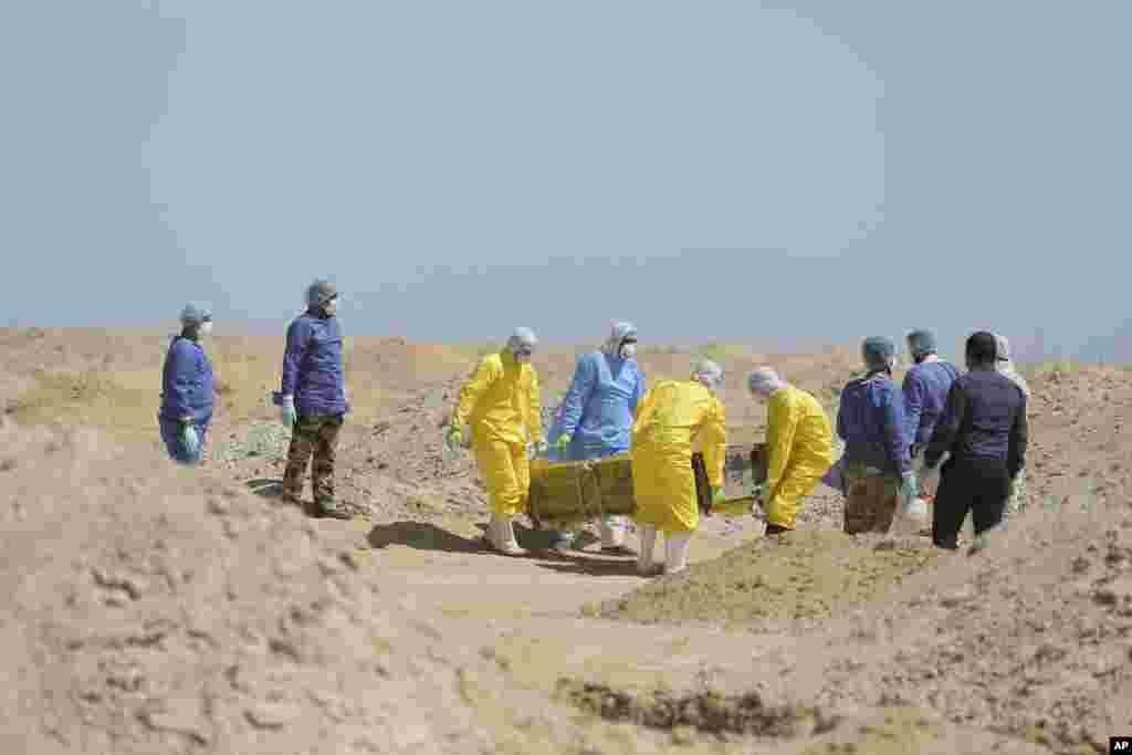 Los trabajadores del Ministerio de Salud iraquí llevan un ataúd a un nuevo cementerio para las personas que murieron de COVID-19, en las afueras de la ciudad de Najaf, Iraq. 