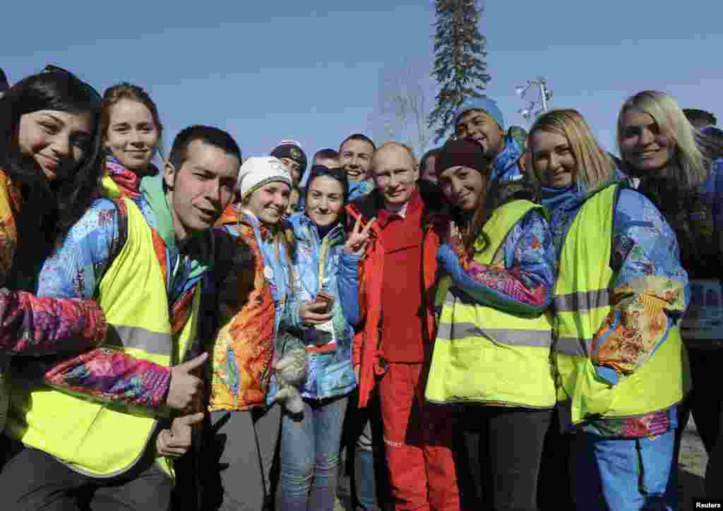 Russian President Vladimir Putin poses for a photograph with volunteers during his visit to watch the men's cross country skiing relay during the Sochi 2014 Olympic Winter Games at Laura Cross-Country Ski and Biathlon Center near Krasnaya Polyana, Russia, Feb. 16, 2014.