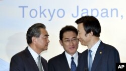Menlu Jepang, Fumio Kishida, tengah memperhatikan saat Menlu China Wang Yi, kiri, berjabat tangan dengan Menlu Korsel, Yun Byung-se setelah konferensi pers seusainya pertemuan trilateral di Tokyo, hari Rabu, 24 Agustus 2016 (foto: Katsumi Kasahara/Pool Photo via AP)