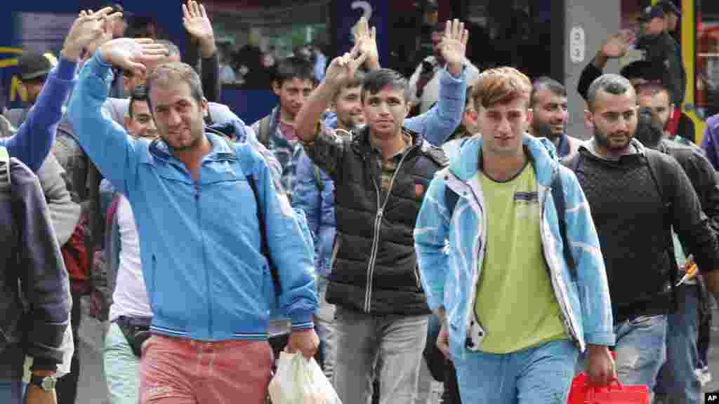 Des réfugiés saluent de la main à leur arrivée à la gare principale de Munich, en Allemagne, 5 septembre 2015.