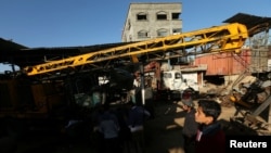 Les Palestiniens inspectent la scène de ce que les témoins ont dit etre une attaque aérienne sur un atelier dans la ville de Gaza , le 5 mai 2016 .