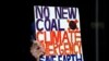 An environmental activist from Extinction Rebellion holds up a placard during a protest against the India-backed Adani coal mine project, outside the GHD engineering office building in Sydney, Aug. 13, 2019. - Scores of environment advocates occupied…