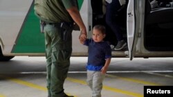 Un agente de la patrulla fronteriza de EE. UU. toma de la mano a un niño que ha entrado irregularmente en el país, en este caso, acompañado de su madre, en busca de asilo, el 15 de marzo de 2021.