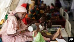 Une femme nourrit un enfant dans un centre hébergeant près de 75.000 personnes qui ont fui les attaques de Boko Haram à Maiduguro, Nigeria, 29 août 2016.