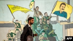مردی در شمال شرق سوریه از کنار تصویر نقاشی شده عبدالله اوجالان عبور می کند - آرشیو