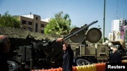 FILE - A man takes a selfie in front of an anti-aircraft weapon on display at Baharestan Square in Tehran, Iran Sept. 27, 2017. 