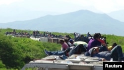 Orang-orang yang ingin masuk ke AS duduk di atas gerbong kereta barang, yang dikenal dengan La Bestia (The Beast) di Ixtepec, negara bagian Meksiko, Oaxaca, 18 Juni 2014. 