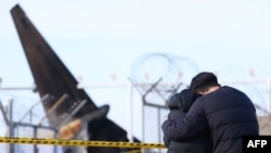 Los familiares en duelo se encuentran en el lugar donde un avión Boeing 737-800 de Jeju Air se estrelló y estalló en llamas este domingo en el Aeropuerto Internacional de Muan en Muan, a unos 288 kilómetros al suroeste de Seúl, el 30 de diciembre de 2024.