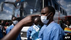 Un membre du Centre biomédical du Rwanda prend la température des passagers à un gare routière à Kigali, le 22 mars 2020 ( AFP / Simon Wohlfahrt )