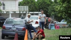 ARCHIVO - Personas esperan llenar de combustible sus vehículos en las afueras de una estación de gasolina de la compañía PDVSA en San Cristobal, Venezuela.