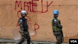 Penjaga Keamanan PBB berjalan melewati tembok tulisan grafiti yang berisi dukungan bagi calon presiden Michel Martelly di Petion Ville dekat Port-au-Prince.