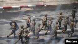 Perwira militer turun tangan selama protes terhadap kudeta militer di Yangon, Myanmar, 2 Maret 2021. Gambar diambil dari balik jendela. (Foto: Reuters)