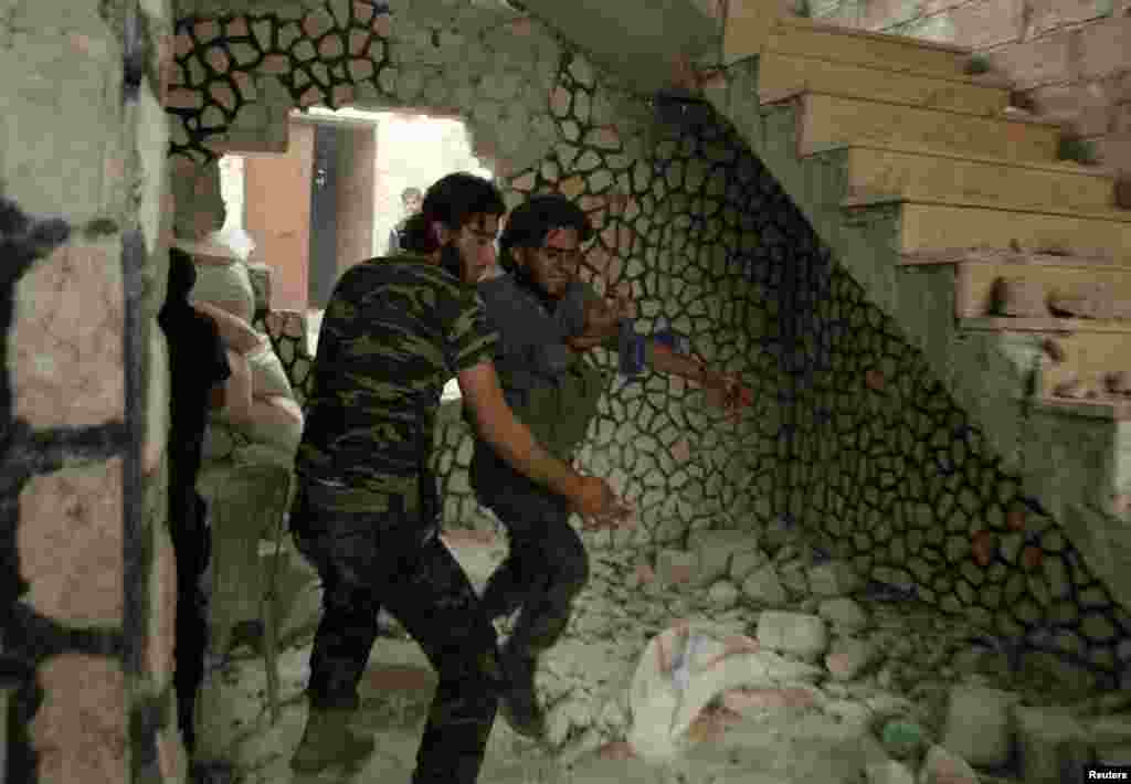 A Free Syrian Army fighter helps another wounded rebel fighter, Al-Amariya district, Aleppo, May 8, 2014.
