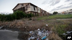 A pile of garbage sits in front of an abandoned section of an apartment complex which was destroyed in 2005 by Hurricane Katrina, in New Orleans, Louisina, Aug. 6, 2015.