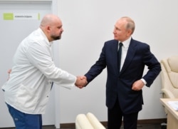 FILE - Russian President Vladimir Putin, right shakes hands with the hospital's chief Denis Protsenko during his visit to the hospital for coronavirus patients, March 24, 2020.