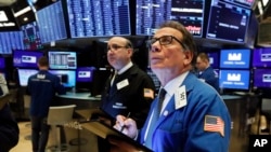 Traders Andrew Silverman, left, and Sal Suarino work on the floor of the New York Stock Exchange, Feb. 25, 2020. 