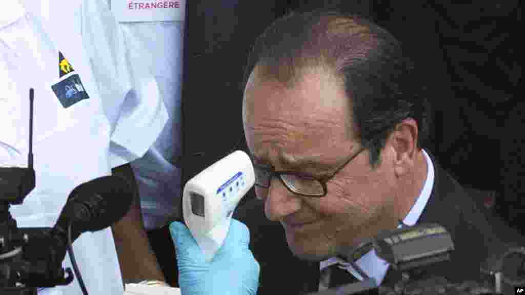 Le président français François Hollande se fait prélever la température à son arrivée à l'hôpital Donka, Conakry, en Guinée, vendredi 28 novembre 2014.