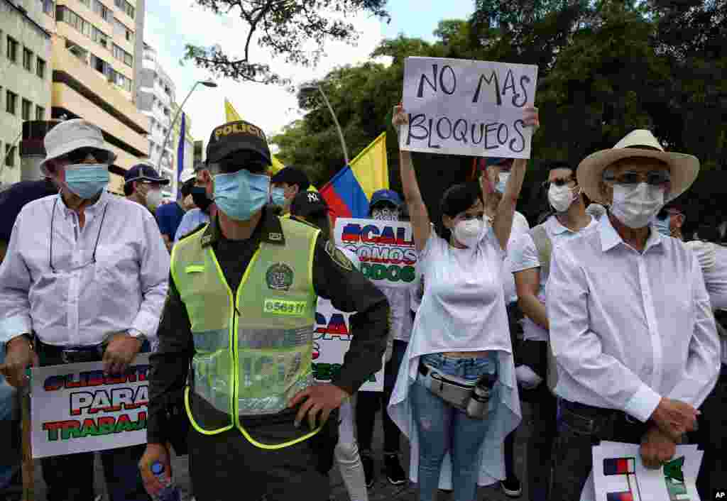 Una mujer sostiene un cartel que dice en español "No más bloqueos" durante la marcha silenciosa para apoyar el desbloqueo de la ciudad.