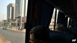 Des passagers à bord d’un bus regardent le siège de la Nigerian National Petroleum Company (NNPC) à Abuja, Nigeria, 13 décembre 2006.