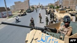 FILE - Afghan National Army commando forces stand guard along a road amid ongoing fighting between Taliban and Afghan security forces in the Enjil district of Herat province, August 1, 2021.