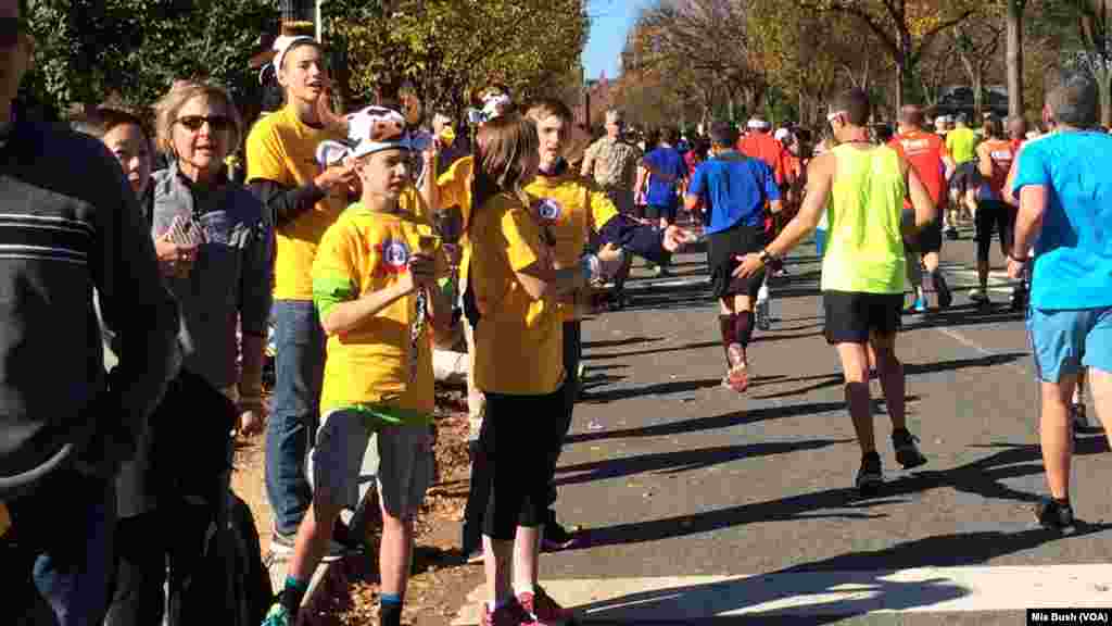 Teens wearing cow-horn hats and ringing cow bells cheer on runners in the Marine Corps Marathon along Independence Avenue Sunday.