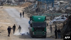 Palestinci trče da uzmu boce sa vodom nakon što su ispale iz kamiona koji prevozi humanitarnu pomoć u Gazi. (Foto: Eyad BABA/AFP)