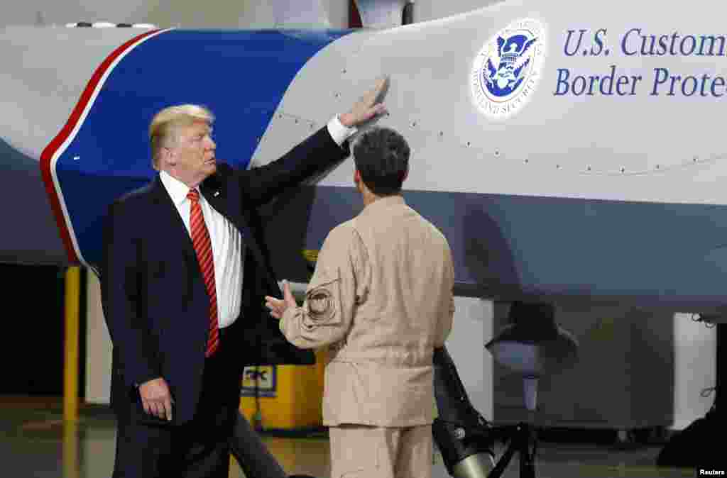 U.S. President Donald Trump puts his hand on a drone aircraft used to patrol the border at U.S. Customs and Border Patrol facility in Yuma, Arizona, Aug. 22, 2017.