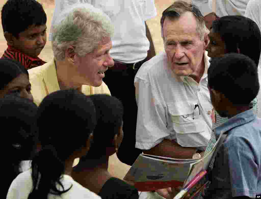 Les anciens présidents américains Bill Clinton et George HW Bush discutent avec des enfants lors d'une visite auprès des personnes déplacées par le tsunami Décembre à Weligama, Sri Lanka, le lundi 21 février 2005.