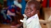 FILE - A child with a thermometer tucked in her armpit cries at a clinic in Nigeria, Aug. 14, 2013. Quackery is a problem in Nigeria, but a new database helps weed out unlicensed doctors.