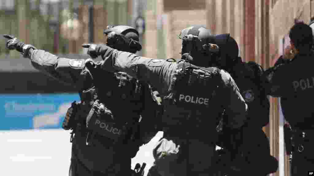 Armed police officers point as they stand at the ready close to a cafe under siege at Martin Place in Sydney, Australia, Dec. 15, 2014.