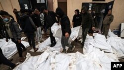 Médicos y voluntarios caminan entre los fallecidos antes de un funeral masivo en el hospital Al-Aqsa en Deir Al-Balah, en el sur de la Franja de Gaza, el 25 de diciembre de 2023.