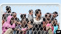 FILE - Migrants wait to disembark from the Italian Navy vessel 'Bettica' in the harbor of Salerno, Italy, May 5, 2015.