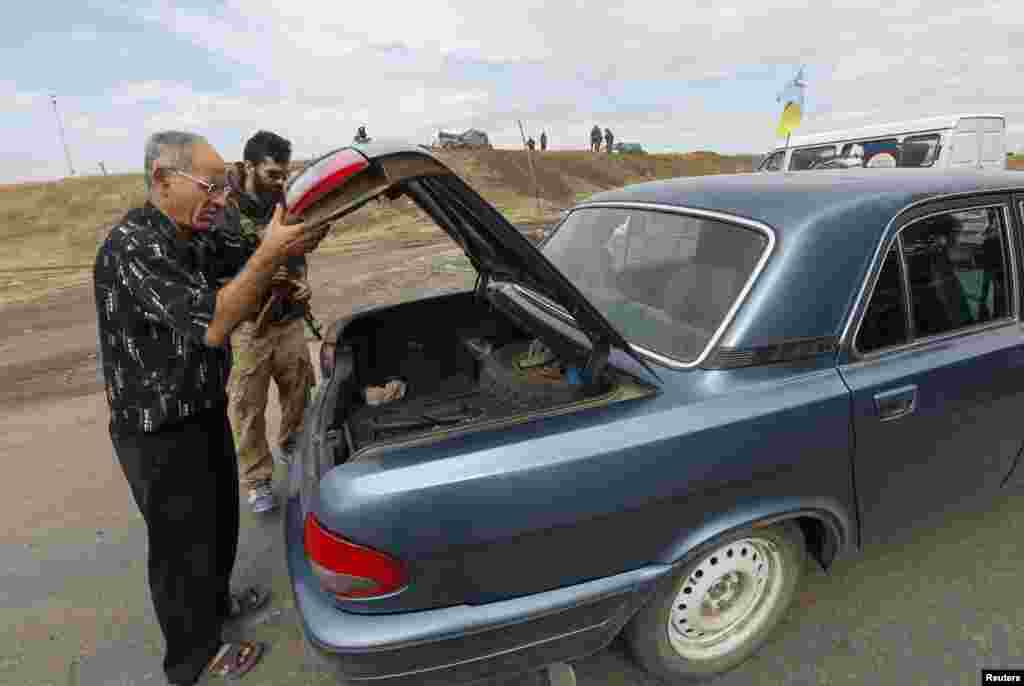 A man opens the trunk of a car for an "Azov" soldier at a checkpoint in Mariupol, Sept. 8, 2014.