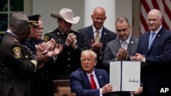 Para pejabat penegak hukum bertepuk tangan setelah Presiden Donald Trump menandatangani perintah eksekutif reformasi polisi di Rose Garden, Gedung Putih, 16 Juni 2020. (AP Photo/Evan Vucci)