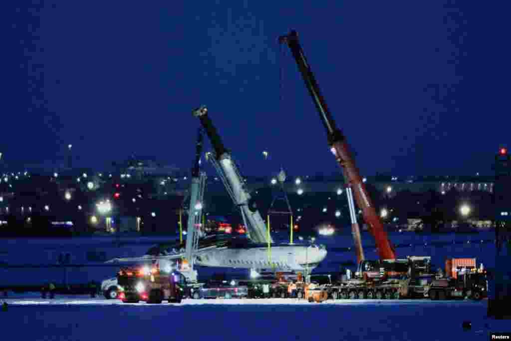 The wreckage of a Delta Air Lines operated CRJ900 aircraft is hoisted onto a truck on the runway as cleanup begins after a plane crash at Toronto Pearson International Airport in Mississauga, Ontario, Canada, Feb. 19, 2025. REUTERS/Cole Burston