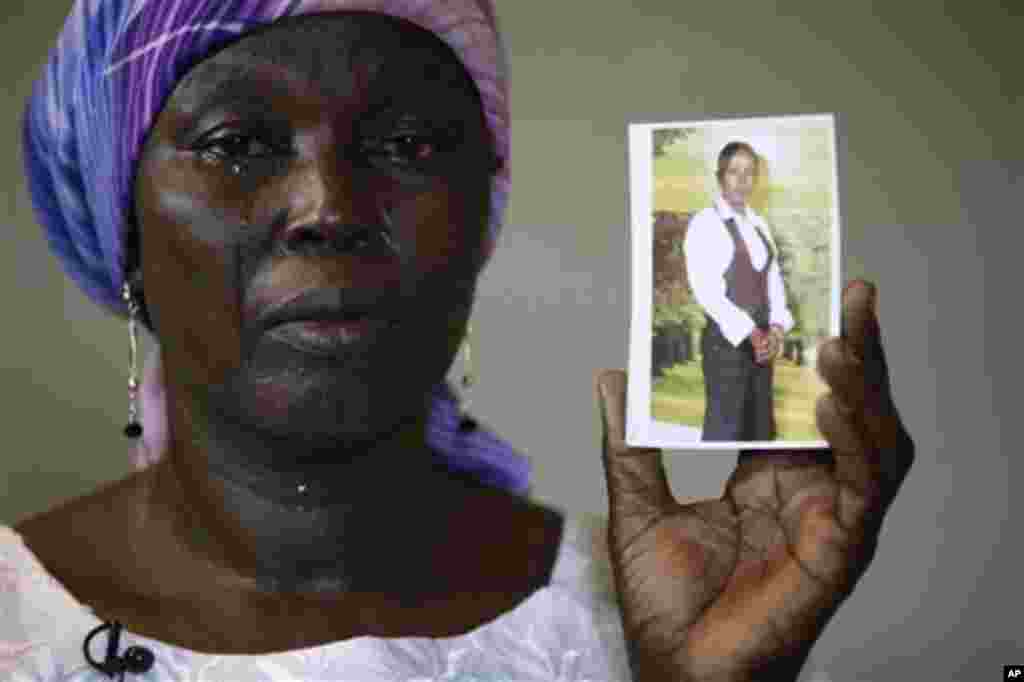 Martha Mark, la mère de l’écolière Monica Mark kidnappée, pleure en montrant la photo de sa fille dans la maison de famille, à Chibok, Nigeria, lundi 19 mai 2014. (AP Photo / Dimanche Alamba, File)