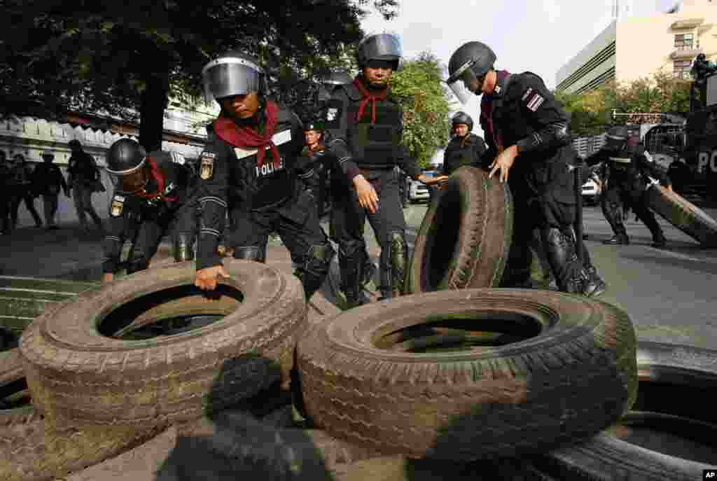 Riot police remove tires and other obstacles as they retake a stretch of a road from anti-government protesters in Bangkok, Feb. 14, 2014.