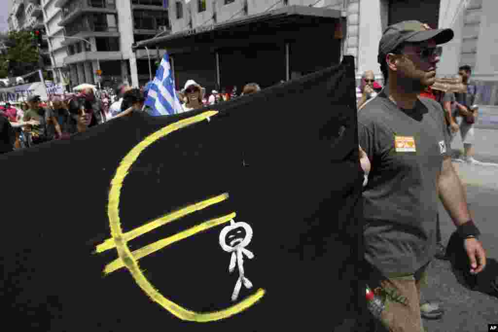 A protester holds a banner featuring a man hanging from a Euro logo as he marches to the Greek Parliament during a protest in Athens, July 16, 2013. 