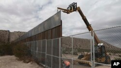 Para pekerja tengah menyelesaikan pembangunan tembok di sepanjang perbatasan AS-Meksiko di kota Anapra, Meksiko dan Sunland Park, New Mexico, 10 November 2016. (Foto: dok). 