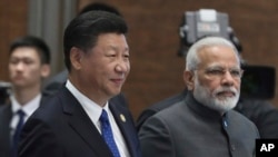 FILE - Chinese President Xi Jinping and Indian Prime Minister Narendra Modi arrive for the Dialogue of Emerging Market and Developing Countries on the sideline of the BRICS Summit in Xiamen, China, Sept. 5, 2017. 