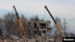 Trabajadores retiran los escombros de un edificio destruido que supuestamente era una escuela de formación profesional utilizada como alojamiento temporal para los soldados rusos, decenas de los cuales murieron en un ataque con misiles ucranianos el 1 de enero de 2023. 